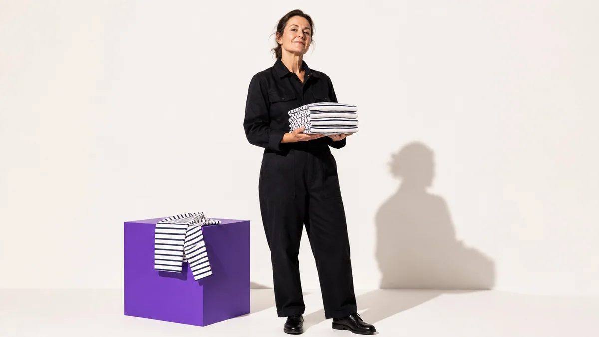 Mise en scène d’une artisane tenant des vêtements marins pliés